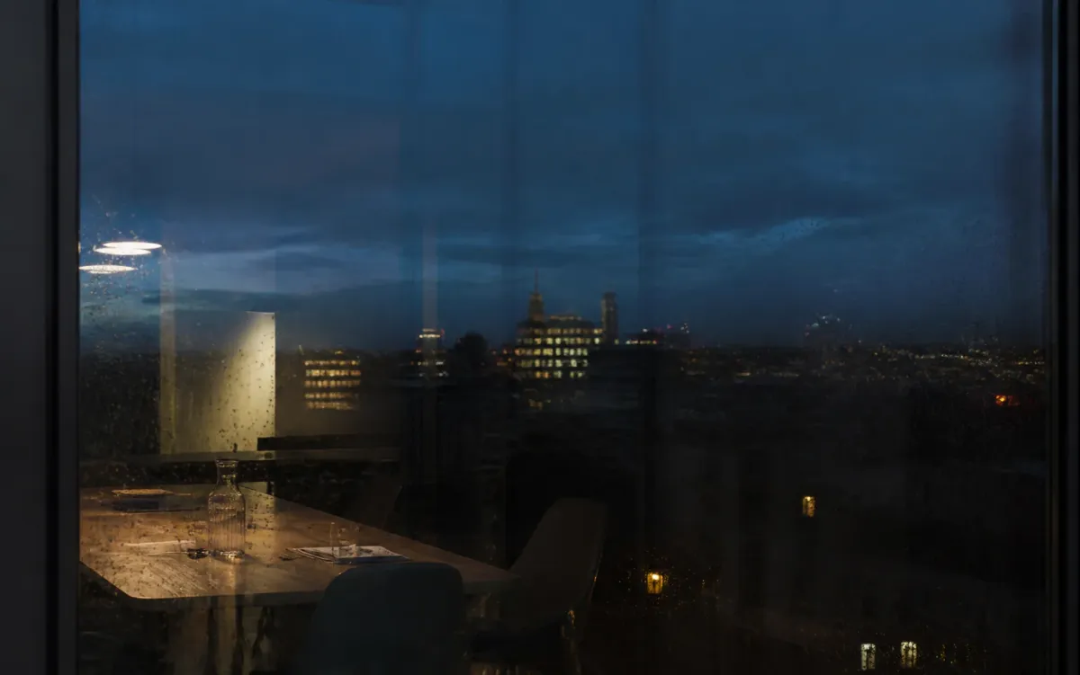 Blick durch ein regennasses Bürofenster in der blauen Stunde