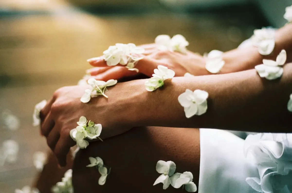 Mit weißen Blüten bedeckte Hände und Beine in einer warmen Ayurveda-Szene