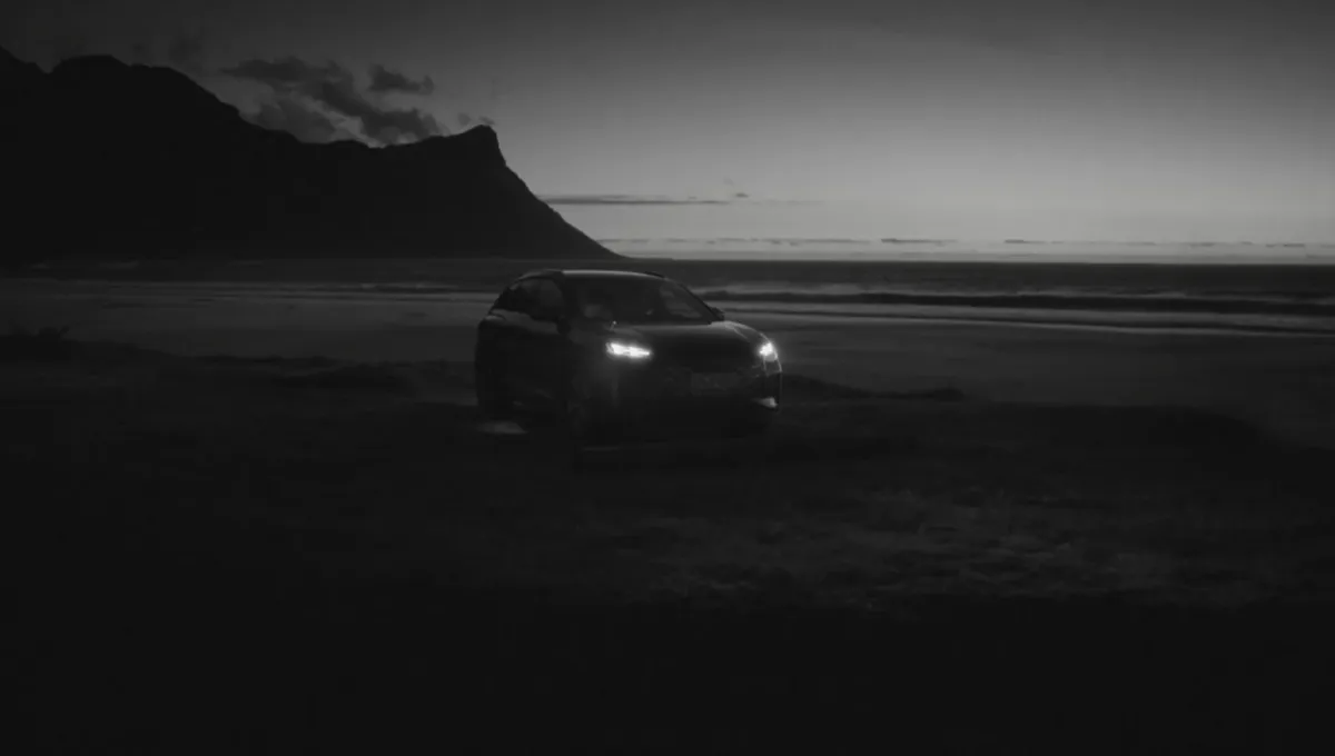 Dunkle Schwarz-Weiß-Aufnahme eines Fahrzeugs vor Bergen und Meer
