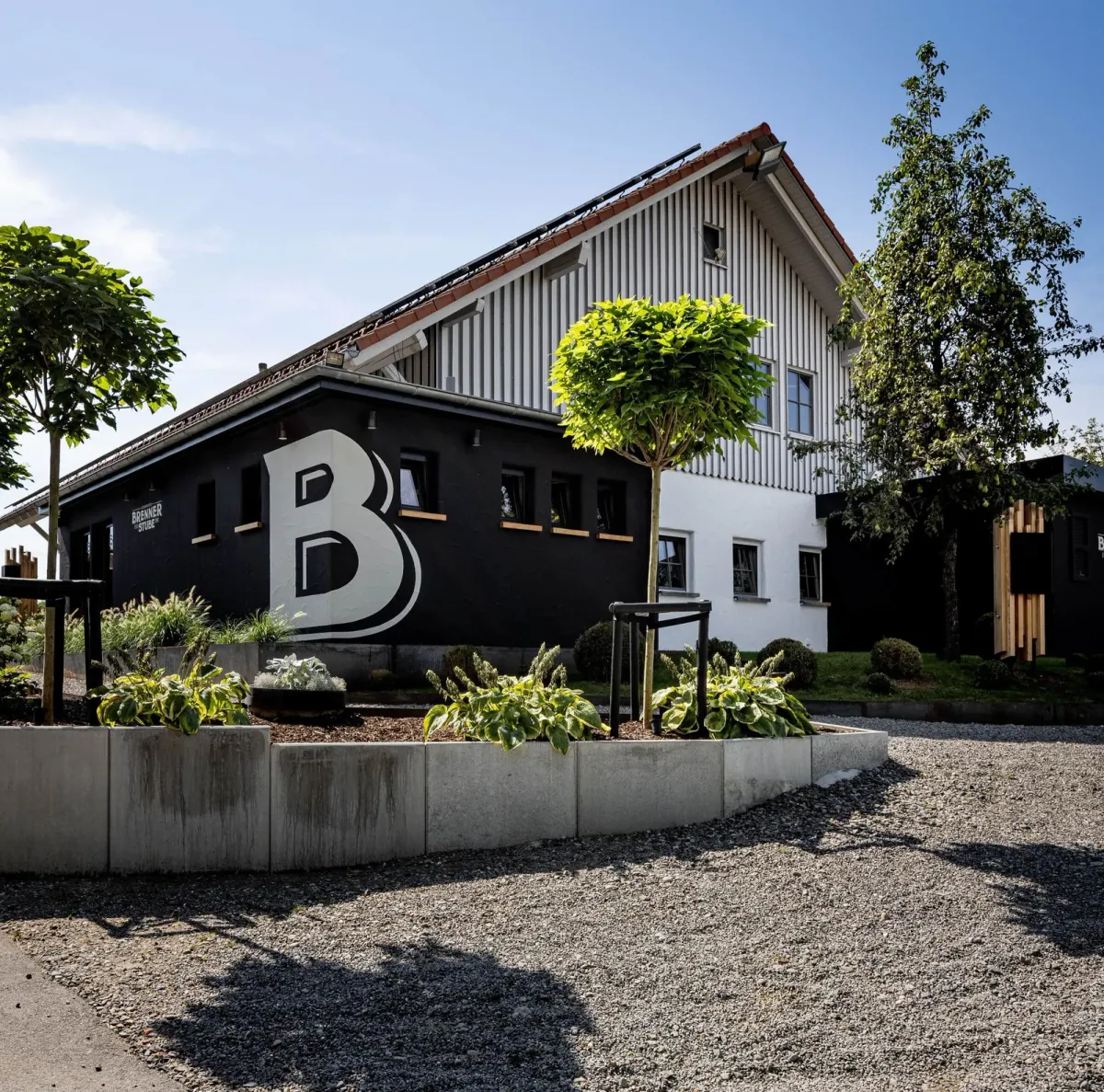Außenansicht der Brenner Stube mit markanter schwarz-weißer Fassade und großem B