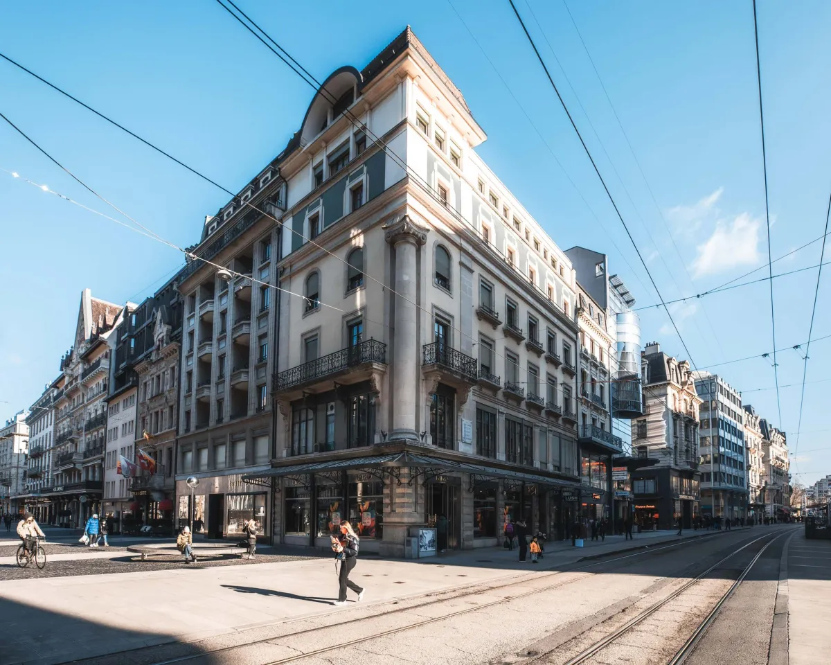 Historisches Geschäftshaus an einer belebten Straßenecke mit Straßenbahnschienen